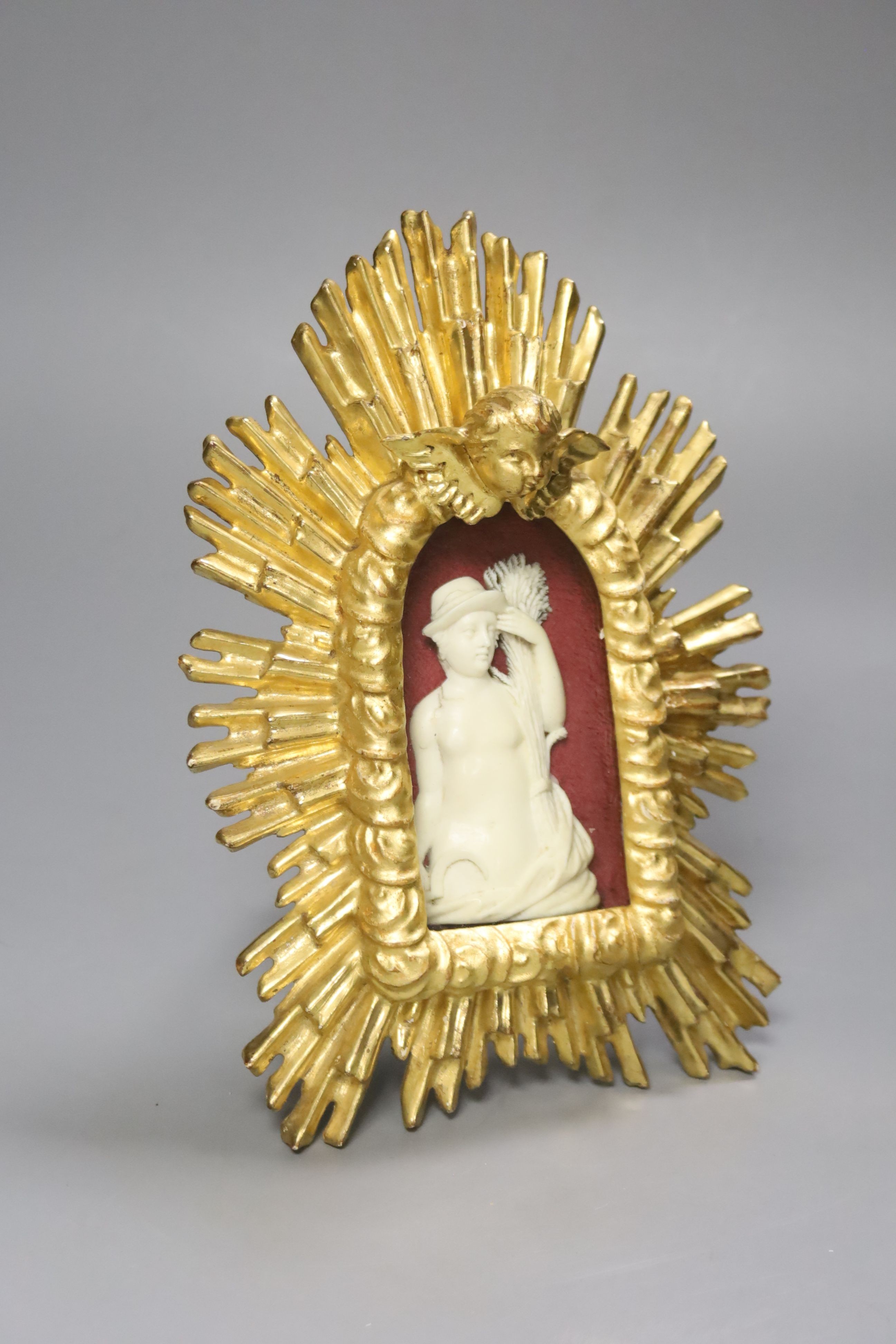 A carved ivory relief figure of a maiden emblematic of agriculture, in a giltwood sunburst frame, length 22cm